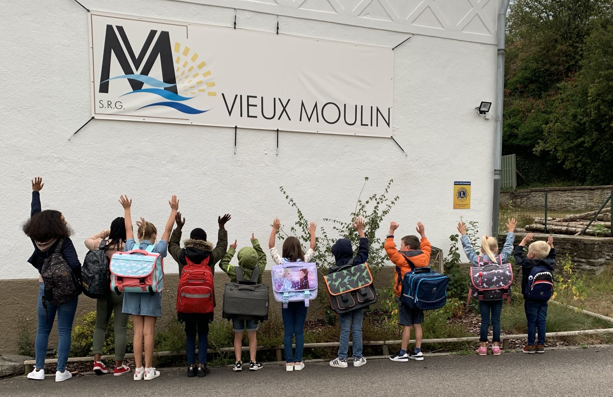 Les enfants du Vieux Moulin devant le logo du Vieux moulin